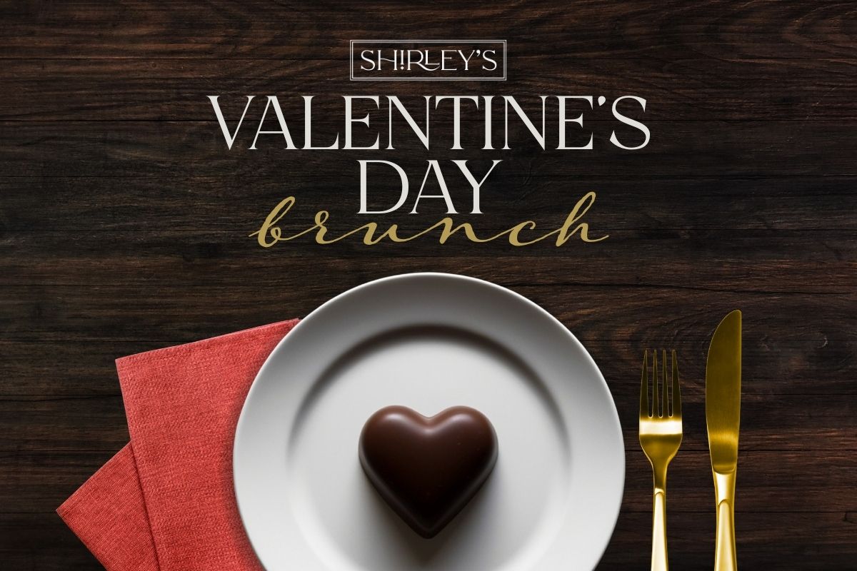 white plate on wood table with chocolate heart, red napkin and gold fork